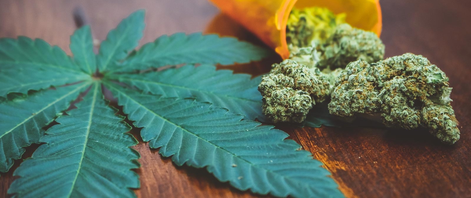 Medical marijuana buds with cannabis leaf on wood table